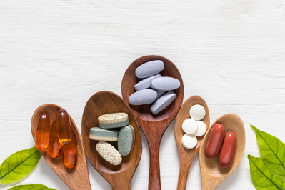 various vitamins and supplements on wooden spoons