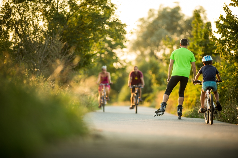 people biking and roller skating on bike path in the evening