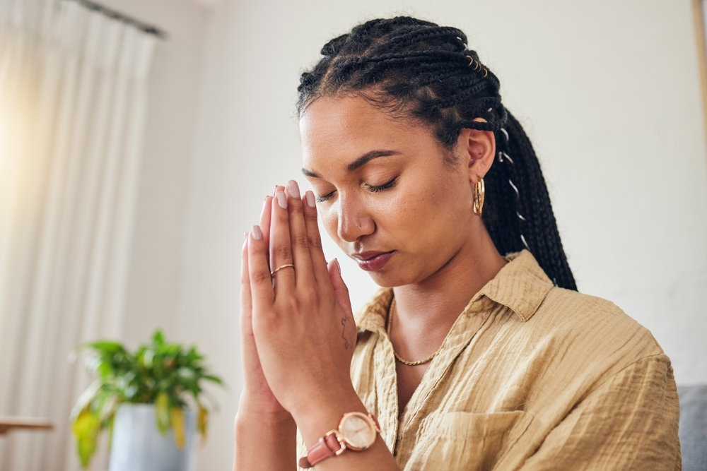 woman with eyes closed and hands together in prayer  or meditation