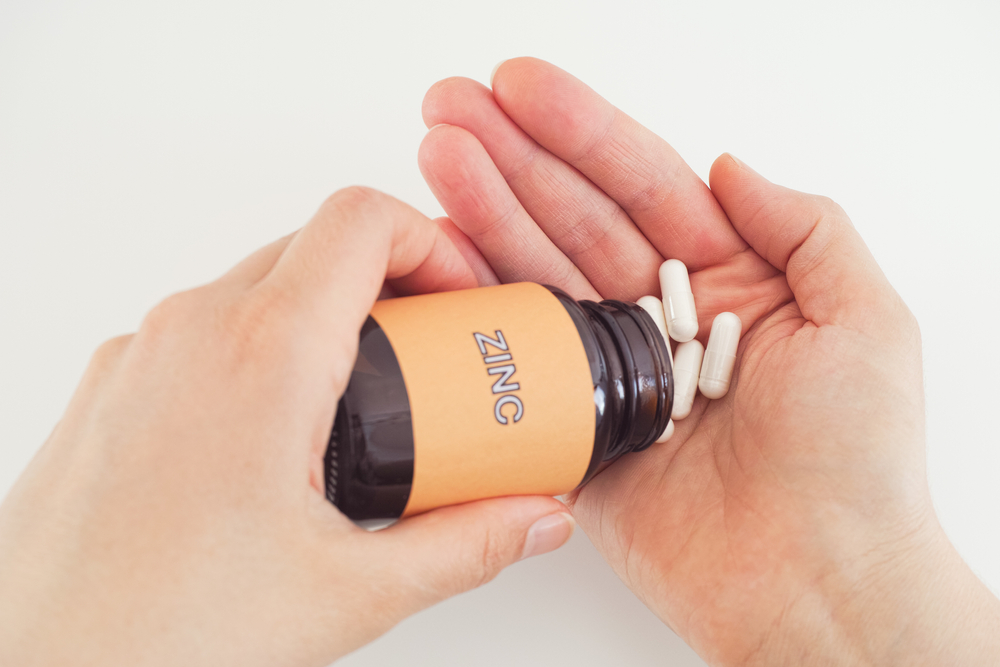 pouring pills from bottle labeled Zinc