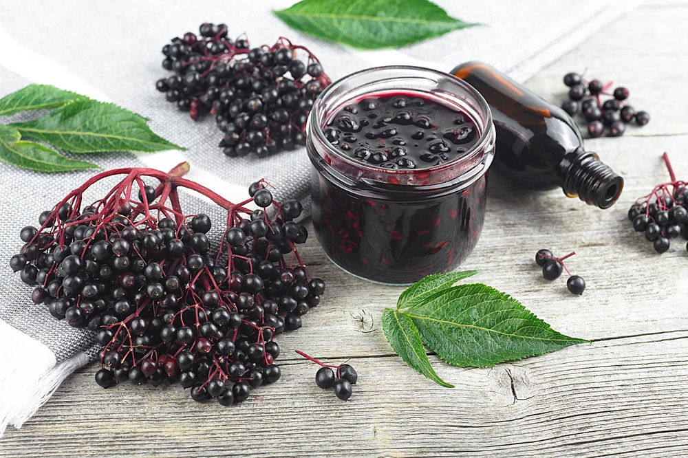 black elderberries next to elderberry syrup