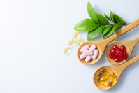 three wooden spoons each with different colored supplement pills and capsules