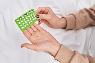 woman's hands taking birth control pill from pill pack