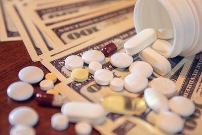 assortment of pills and supplements on pile of $100 bills